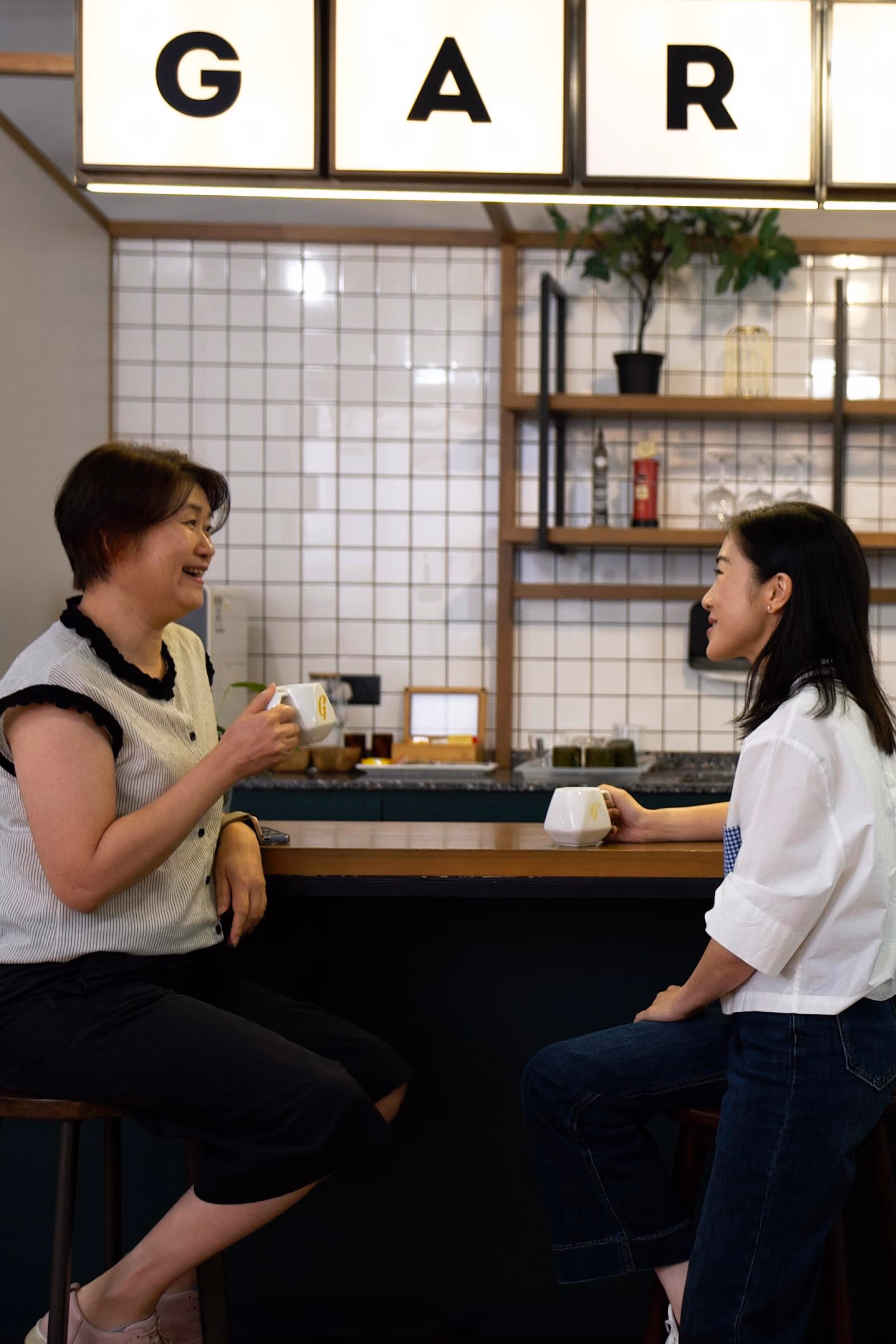 two female office workers have coffee at a coworkspace pantry