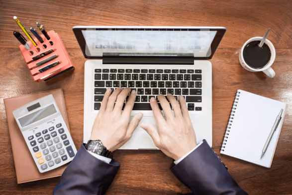 Top view of business man hands working on laptop on wooden desk