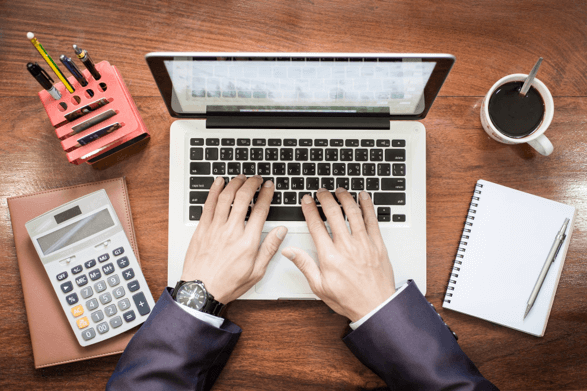 Top view of business man hands working on laptop on wooden desk