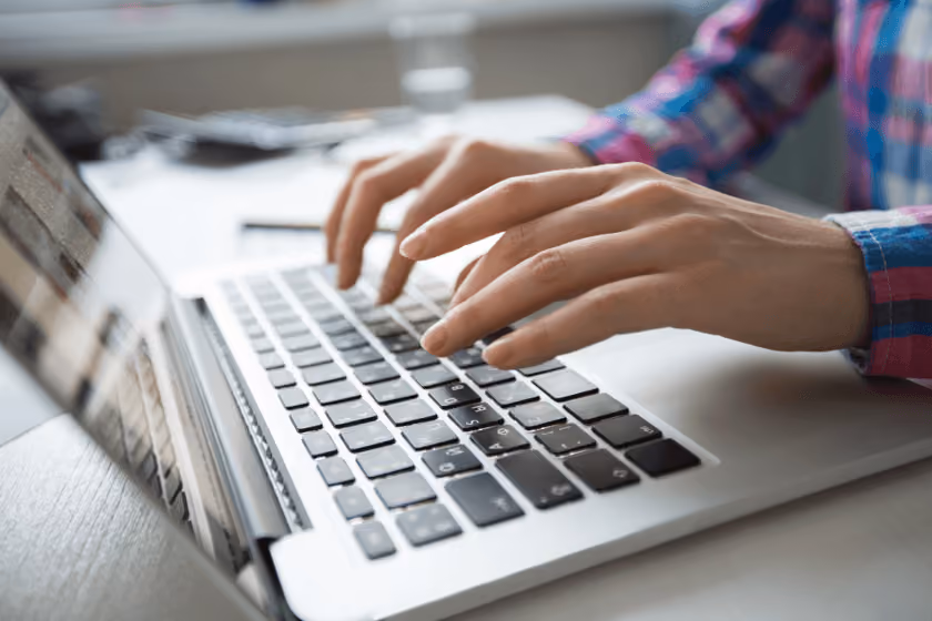 Cropped view of hands typing on laptop