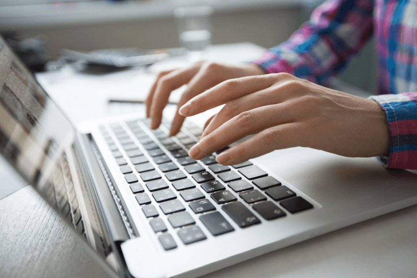 Cropped view of hands typing on laptop