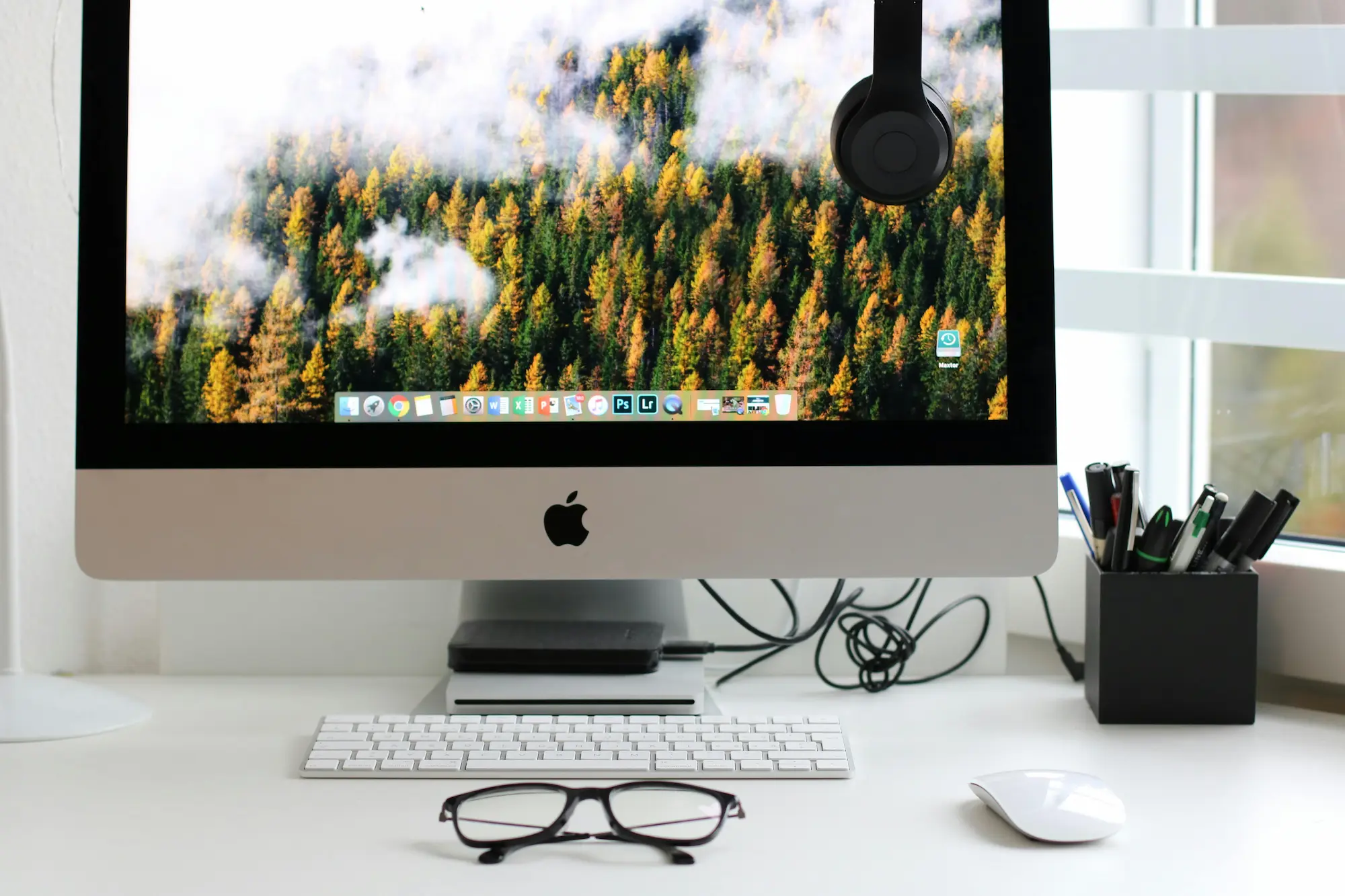 Un mac posé sur un bureau avec un fond d'écran de foret