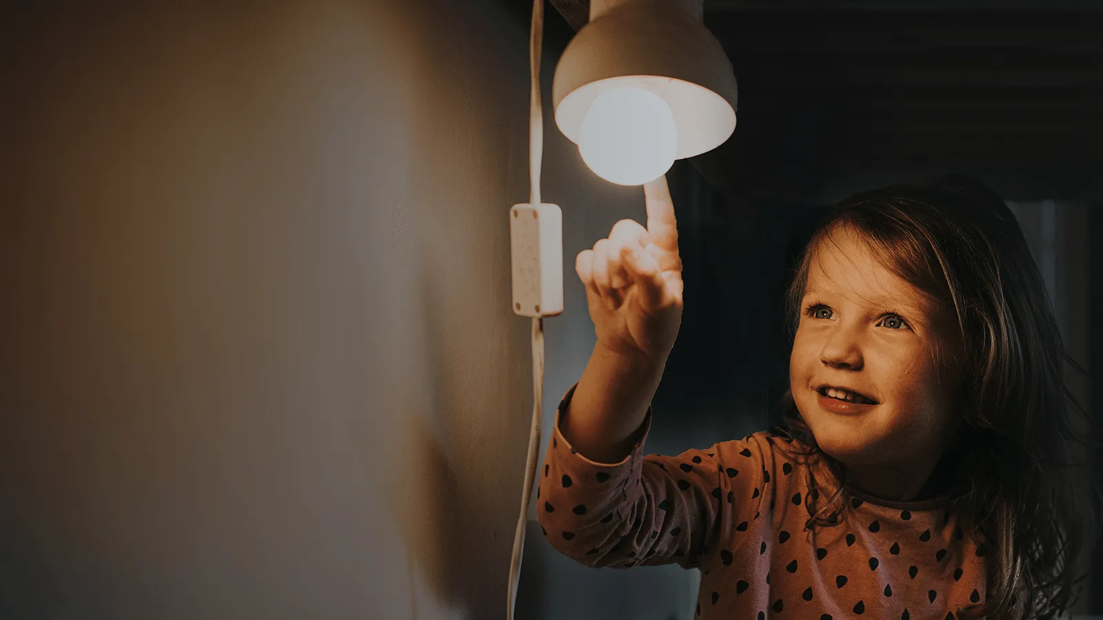 Ett barn rör vid sänglampan med fingret