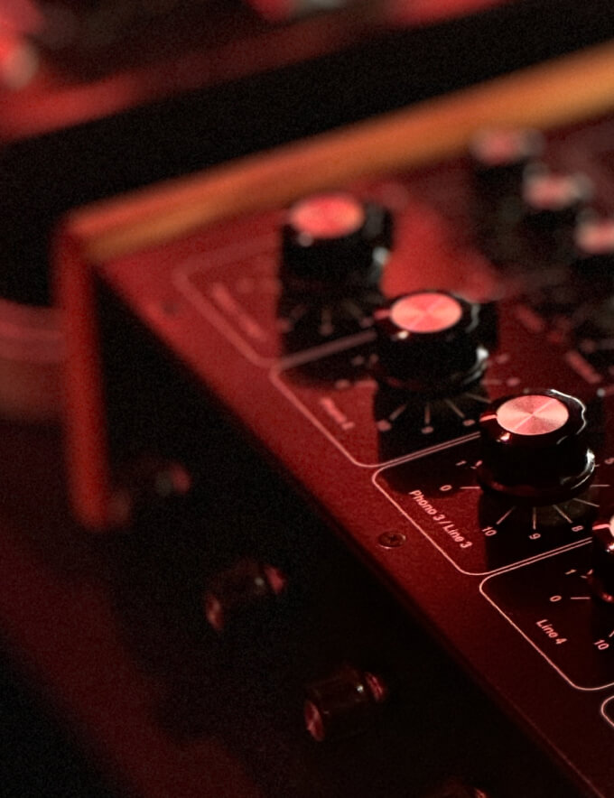 Close-up of black audio mixer knobs with red lighting and labels for phono and line inputs.