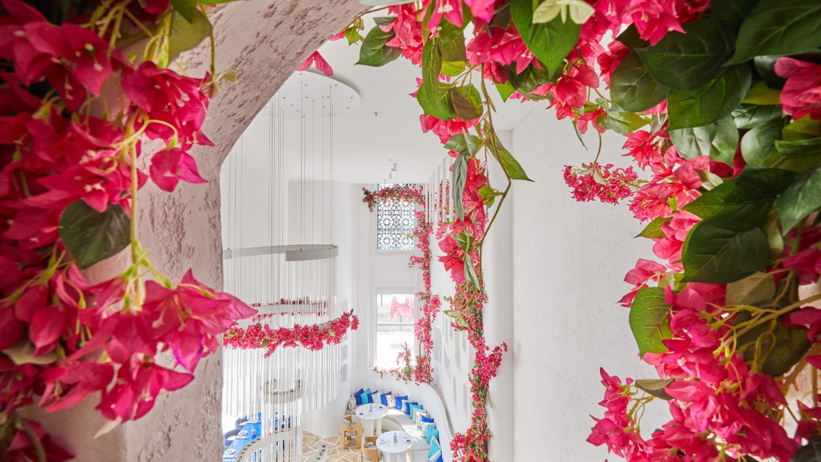 Bright white interior space framed by vibrant pink bougainvillea flowers and cascading vines.