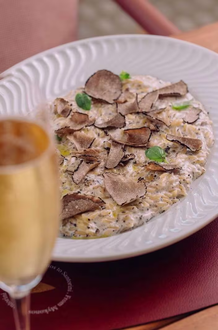 Creamy risotto topped with shaved truffle and microgreens, served with wine glass