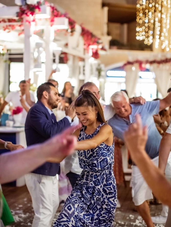 Guests dancing and celebrating at elegant wedding reception with pink flowers and gold decorations