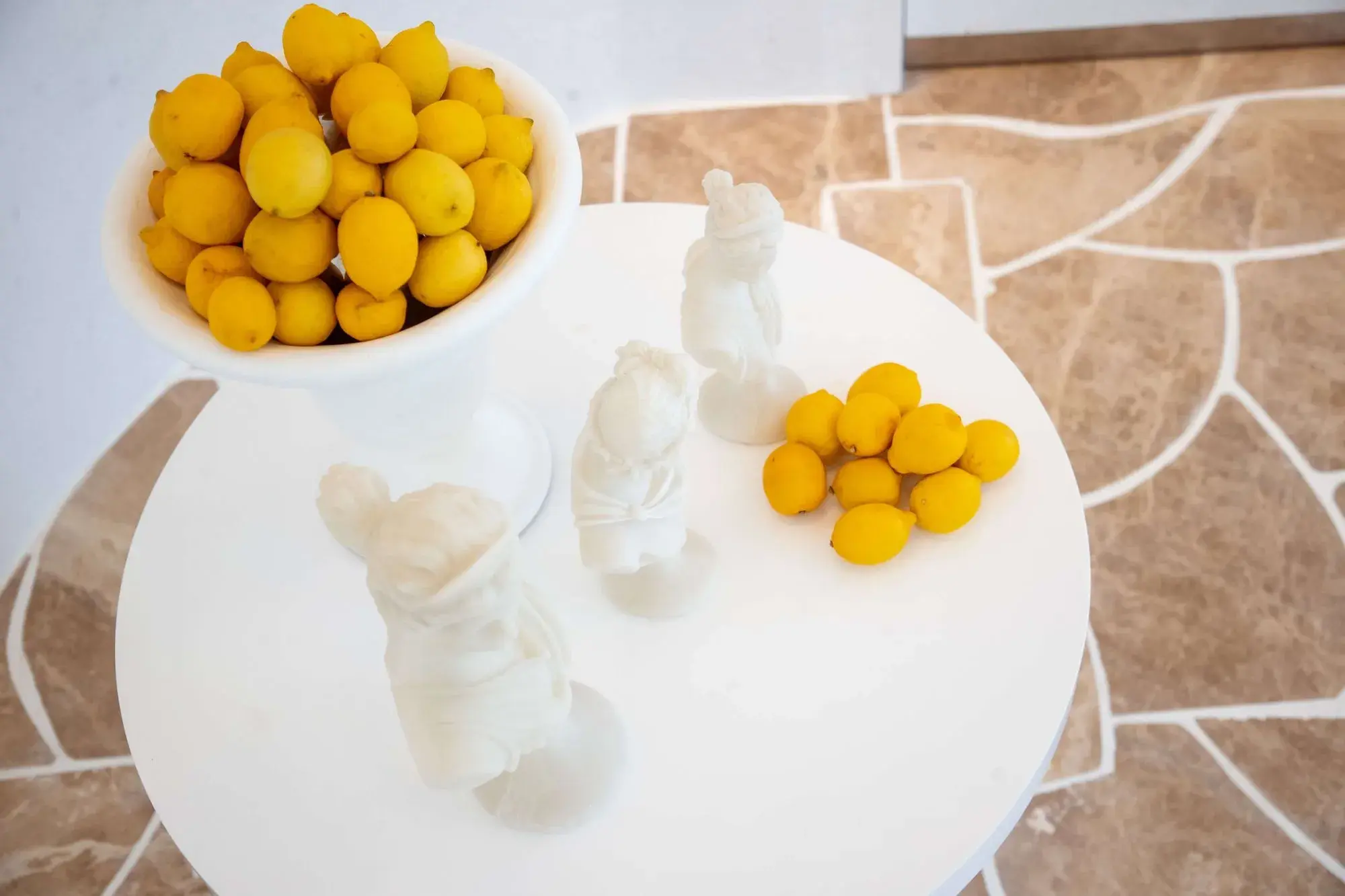 White plates with fresh yellow lemons and white garlic cloves on textured tile background