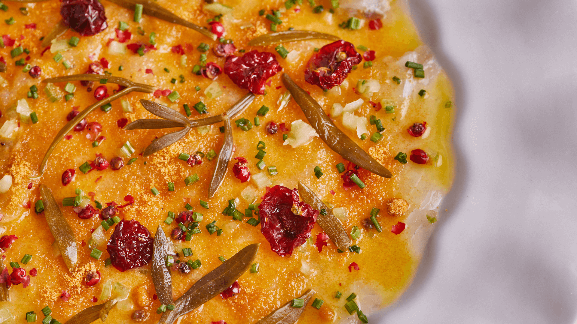 Golden baked salmon topped with fresh herbs, pomegranate seeds, and garnished rosemary sprigs.