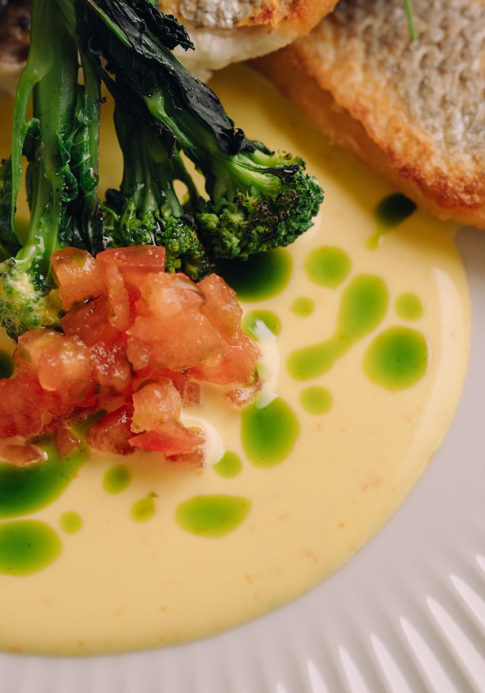 Charred broccoli with caviar on creamy yellow sauce with green dots