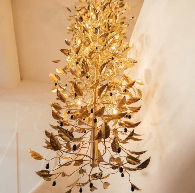 Decorative golden metal tree sculpture with black berries on white walls