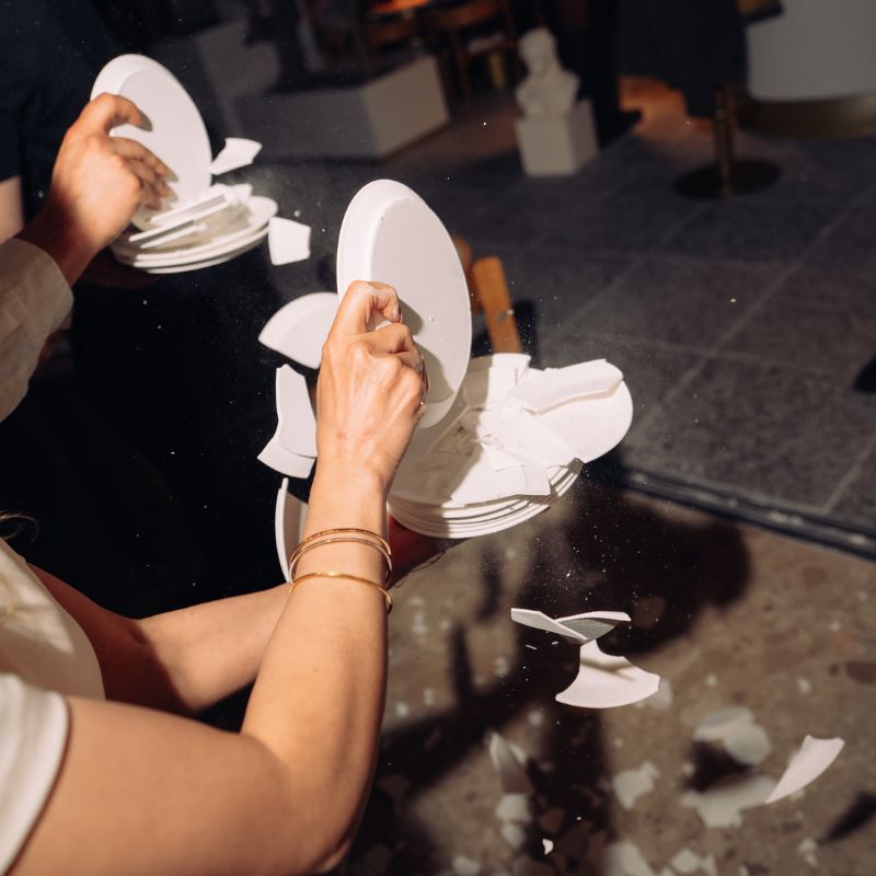 Person holding white paper plates at indoor event or gathering with others