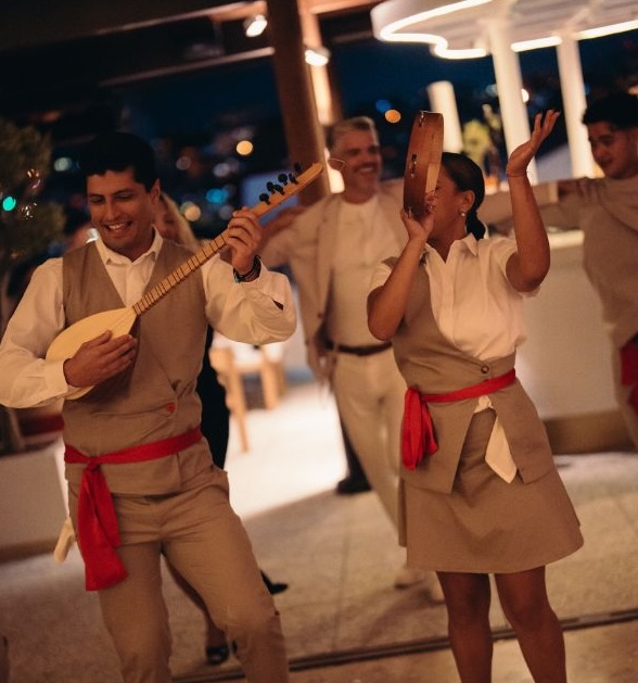 Group of people dancing with musical instruments at nighttime outdoor celebration event