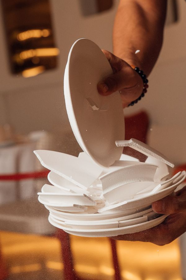 Person holding a stack of white paper plates in warm lighting environment