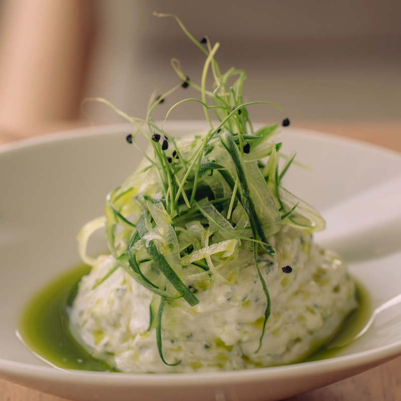Creamy herb-infused risotto garnished with microgreens and black caviar on white plate