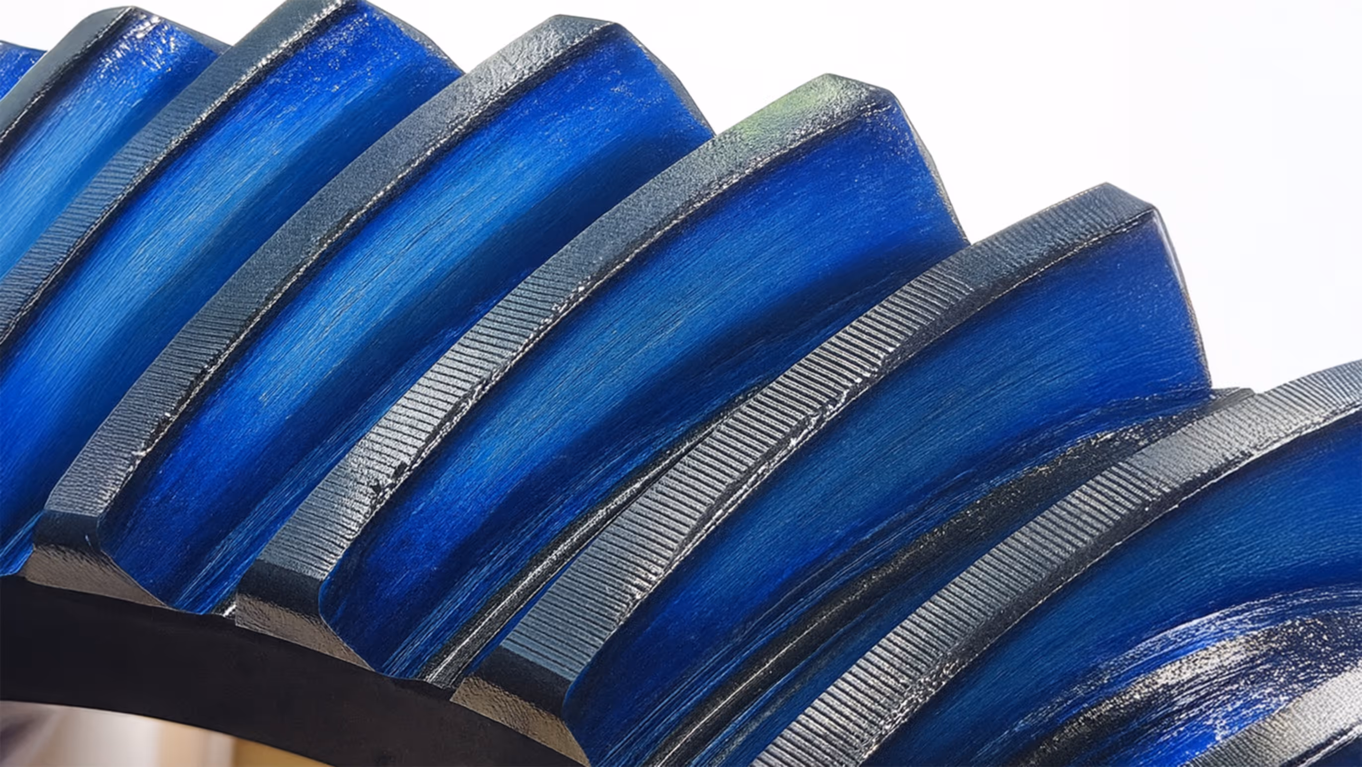 Nahaufnahme eines Zahnrads mit blau beschichteten Zähnen und feinen Einkerbungen auf der Oberfläche.