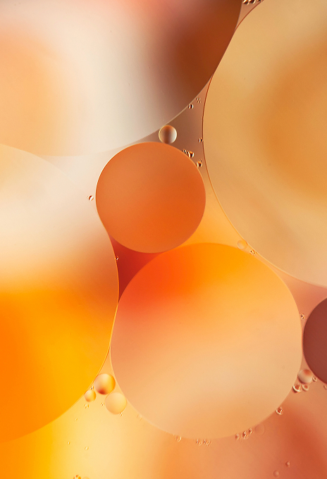 Close-up of orange-toned oil droplets in liquid, representing transformation and the plant-based raw materials used by Simplyfined.