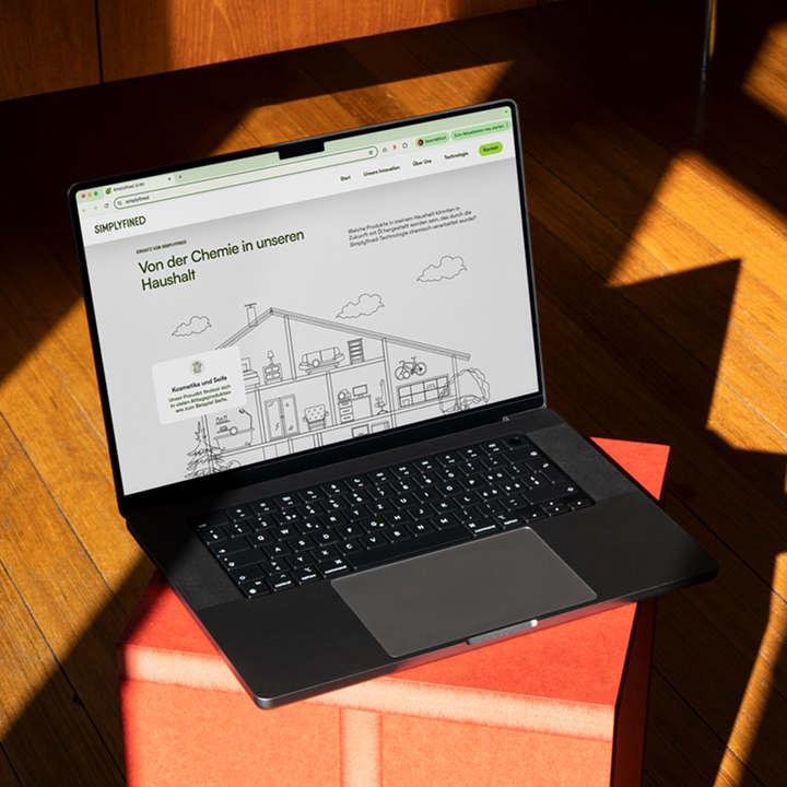 Laptop showing the Simplyfined's landing page with an illustrated house graphic, highlighting everyday household products connected to the start-up’s innovative plant-based oil technology.