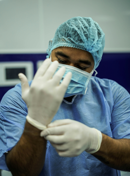 Chirurg zieht vor der Operation im Krankenhaus sterile Handschuhe an — Bilder aus dem Gesundheitswesen von Pharos Labs
