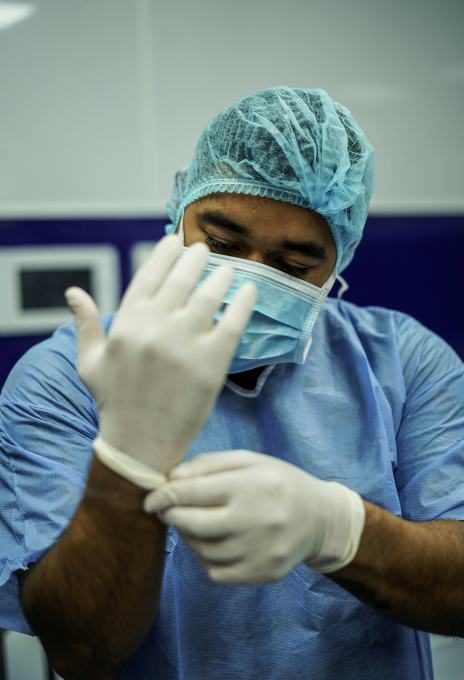Chirurg zieht vor der Operation im Krankenhaus sterile Handschuhe an — Bilder aus dem Gesundheitswesen von Pharos Labs