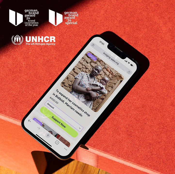 Smartphone, auf dem die Spendenplattform von Bridging Gaps mit einem Unternehmerprofil und der Schaltfläche „Jetzt unterstützen“ auf einer roten Oberfläche angezeigt wird. Die obigen Logos heben Auszeichnungen des German Brand Award 2024 und eine Partnerschaft mit dem UNHCR hervor.