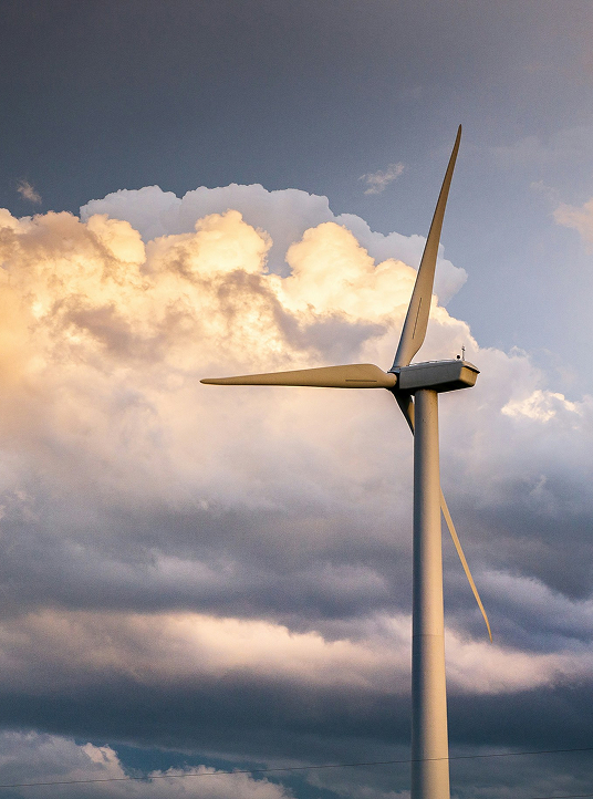 Eine Nahaufnahme einer Windturbine, die hoch vor einem dramatischen Himmel voller goldener Wolken steht, die erneuerbare Energien symbolisieren.
