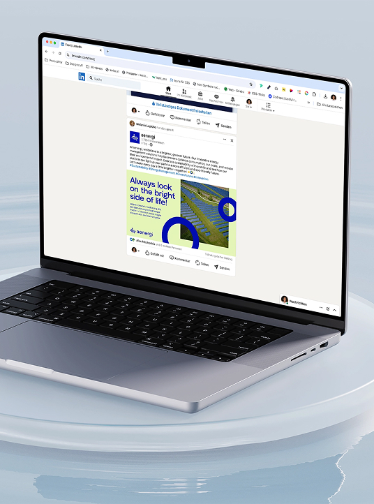 Öffnen Sie den Laptop, auf dem ein LinkedIn-Beitrag von aenergi angezeigt wird, auf dem eine Grafik mit blauen und grünen Formen und dem Text „Always look on the bright side of life!“ zu sehen ist.