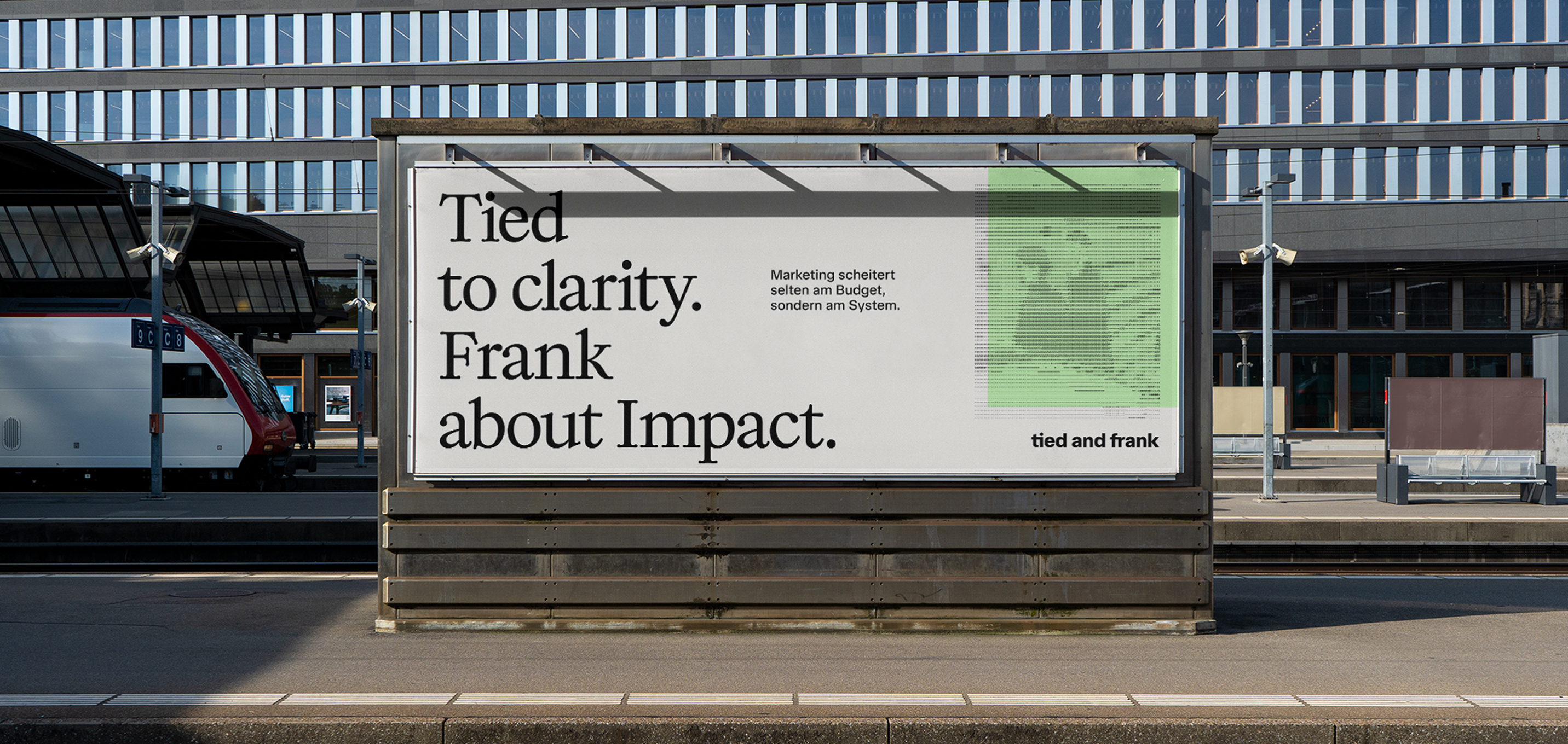 Bahnsteig mit einer großen Werbetafel mit der Aufschrift „Tied to Clarity“. Frank über Impact. „neben einem Zug auf der linken Seite und modernen Gebäudefenstern im Hintergrund.