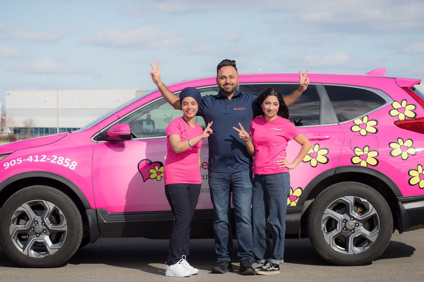 nurse next door franchisees in front of the pink car.