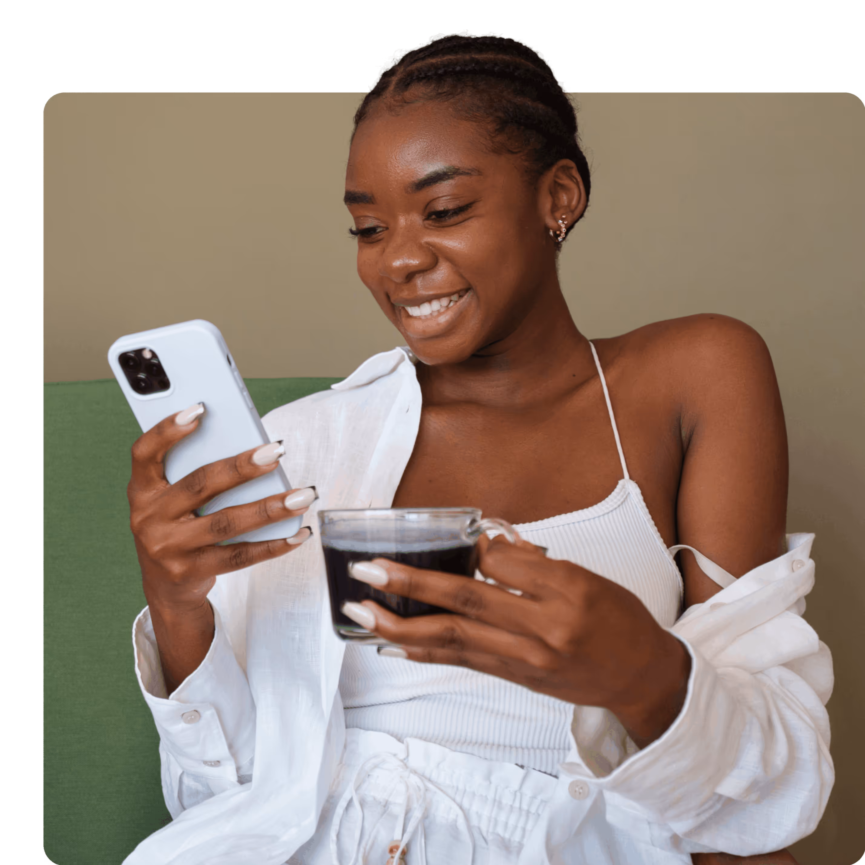 Happy Girl Sitting Looking at her smart phone with a tea cup in her other hand.