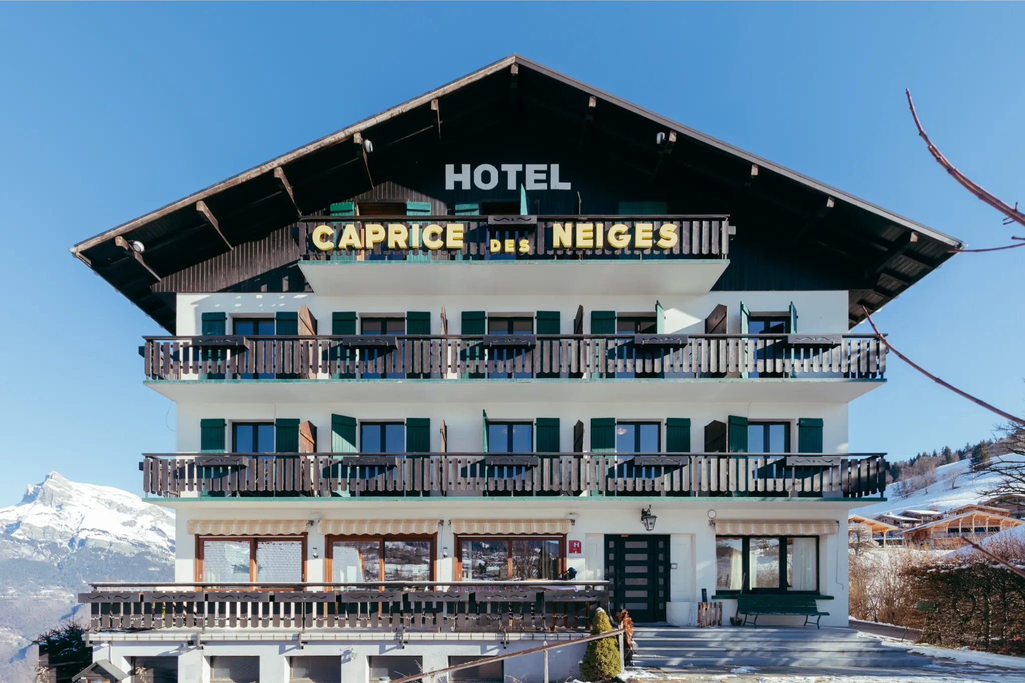 Entrée principale du Caprice des Neiges, hôtel de charme à Combloux avec façade en bois typique.