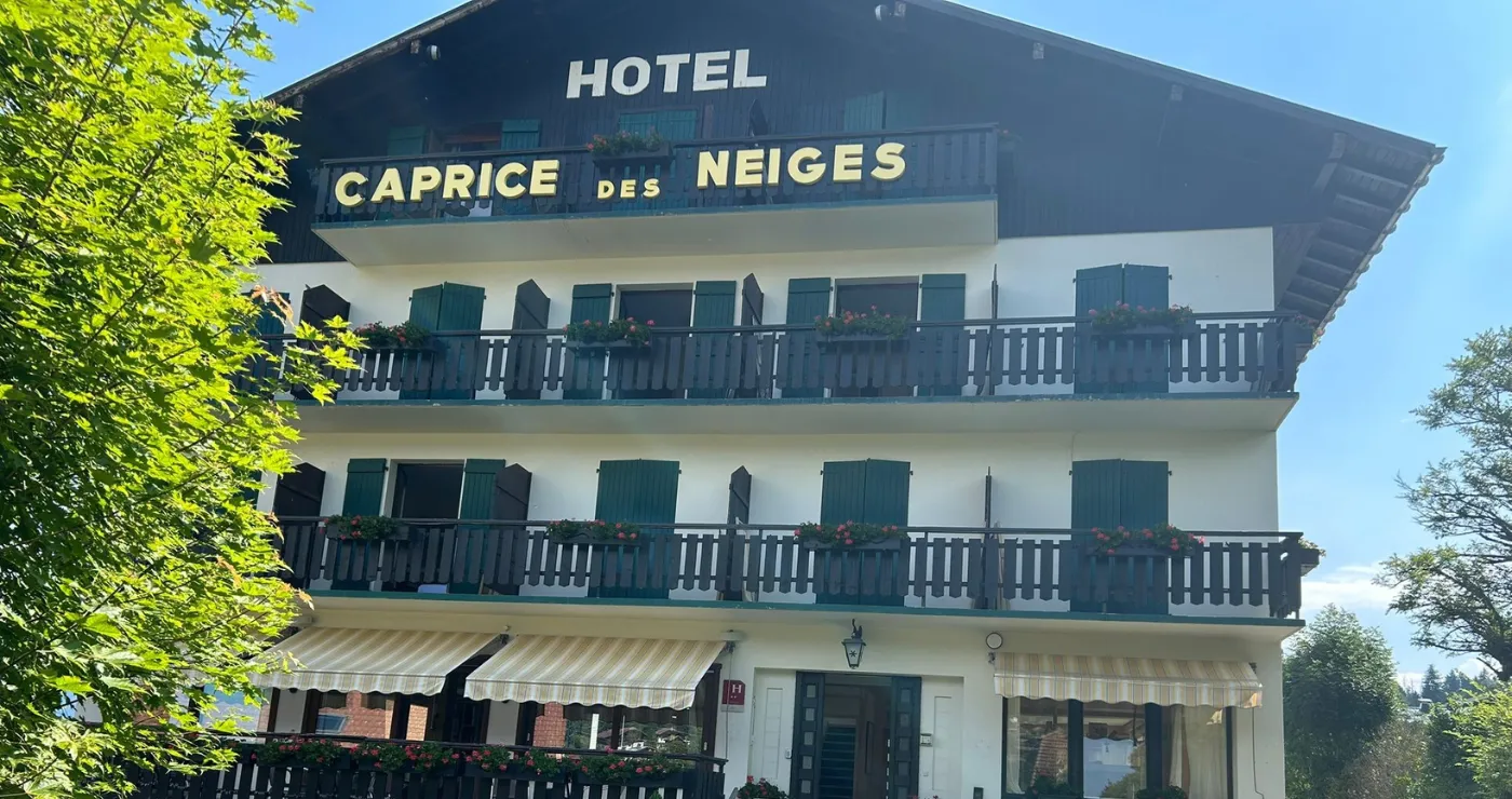 View of the façade of the Caprice des Neiges, a typical Savoyard hotel with wood and stone architecture in Combloux.
