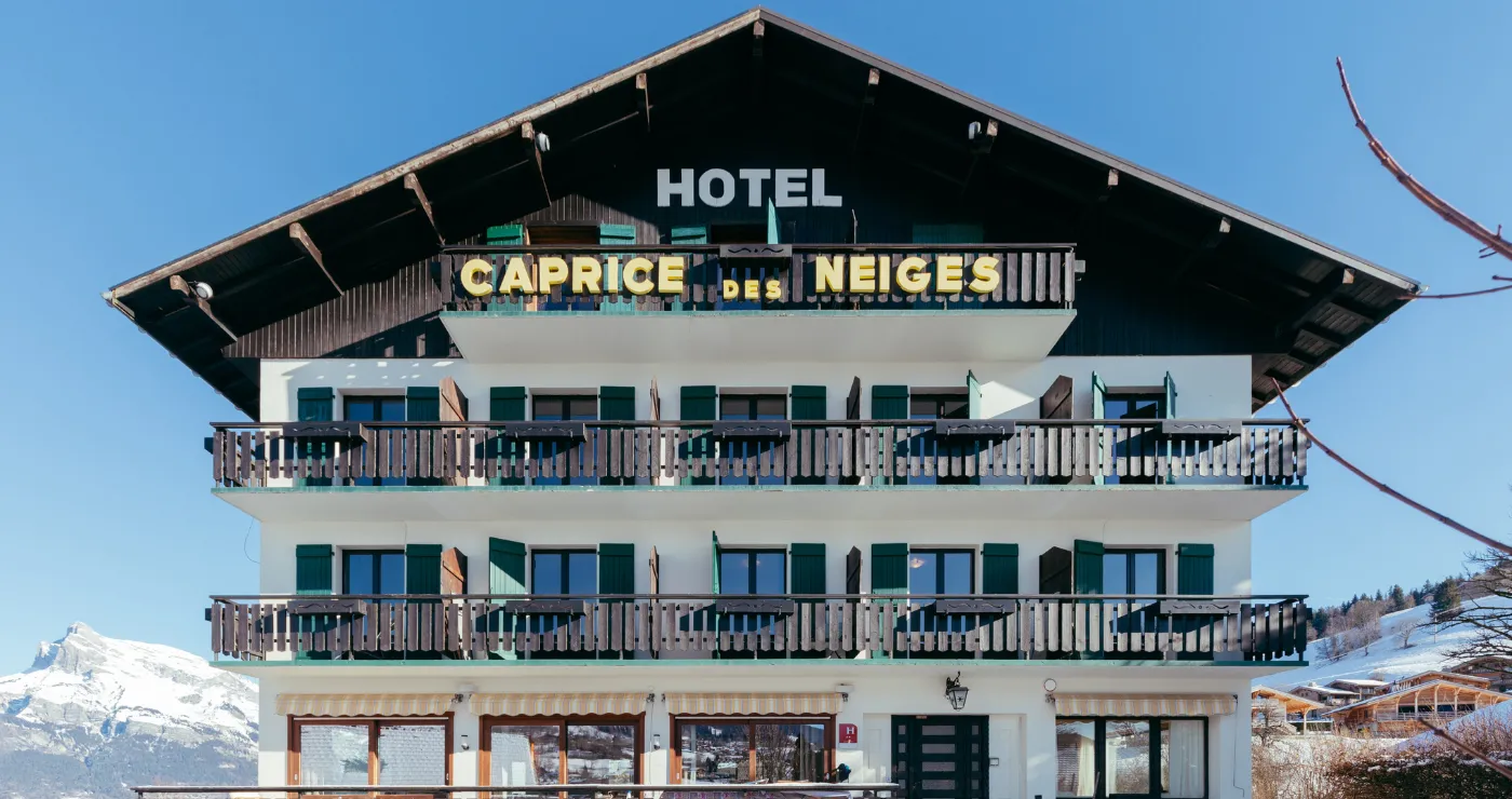 Frontage of the Caprice des Neiges, a charming hotel in Combloux with traditional mountain architecture.