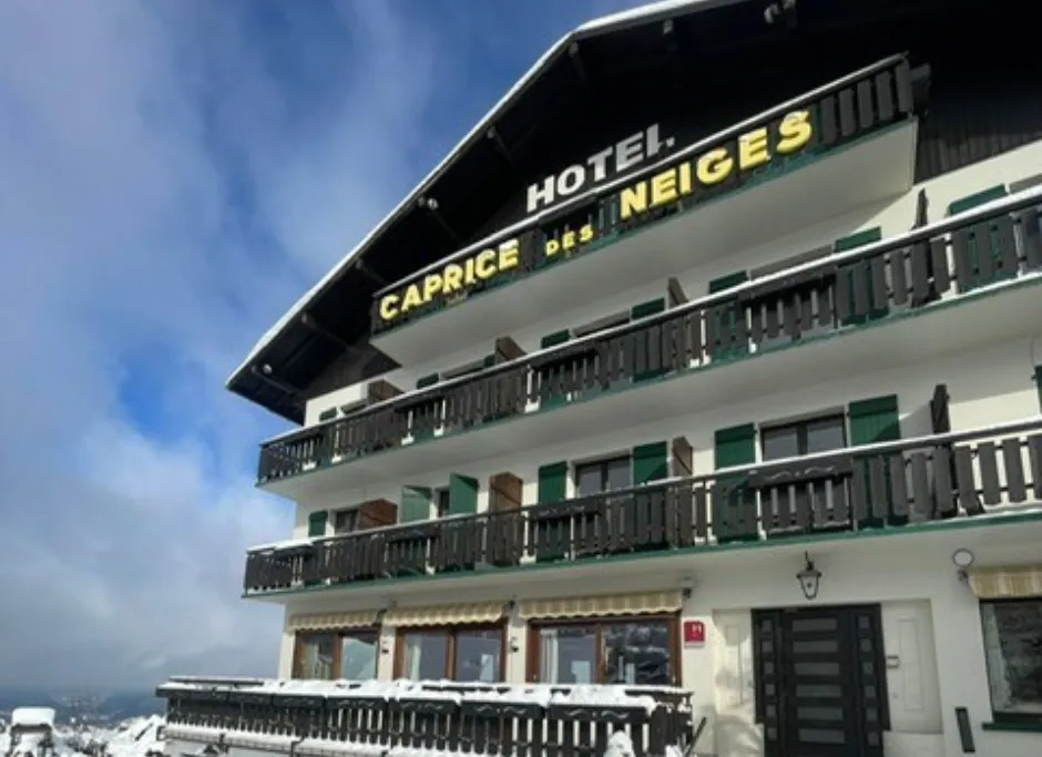 Wood and stone facade of the Le Caprice des Neiges hotel in Combloux, in a peaceful Alpine setting.