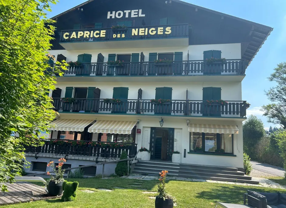 The facade of Le Caprice des Neiges seen from afar, surrounded by Combloux's alpine peaks.