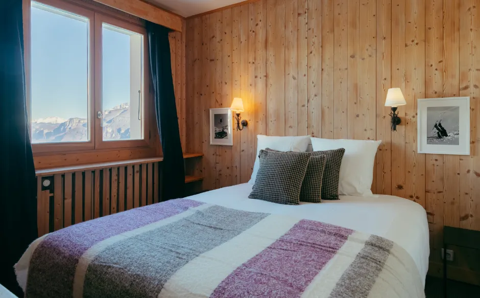 Premium room at the Caprice des Neiges with cozy bed and elegant Alpine decor.