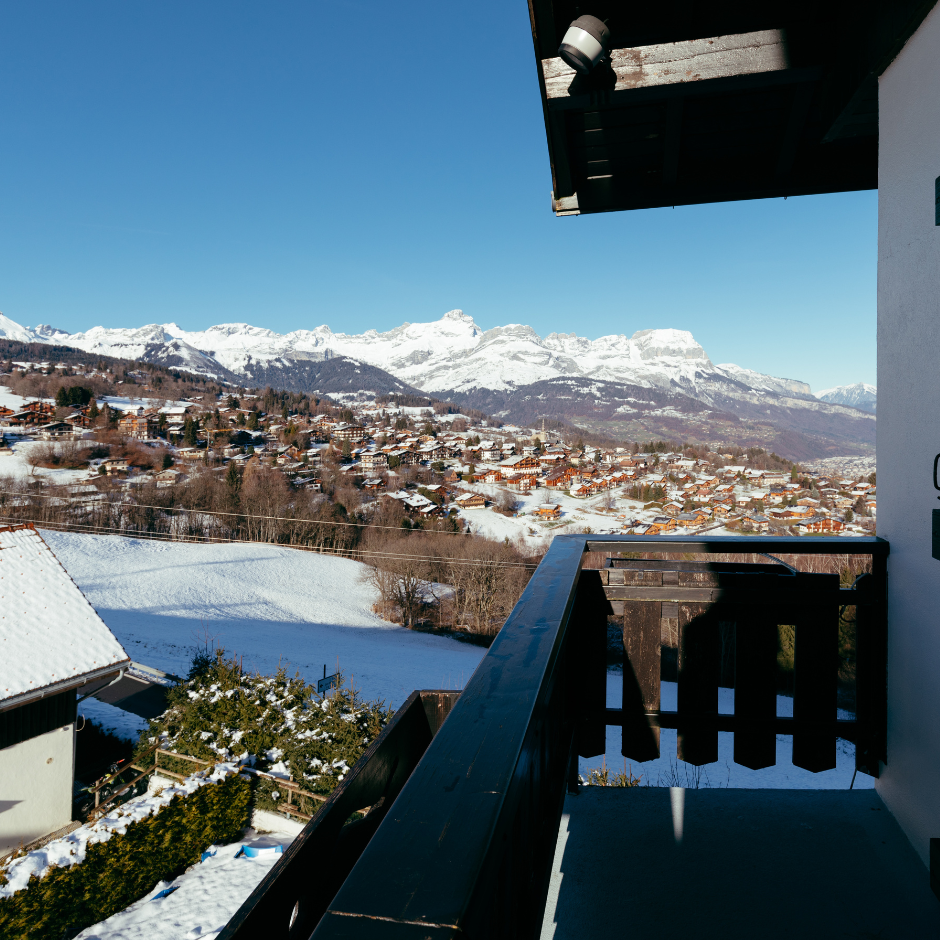 Balcon avec vue sur le village de Combloux enneigé et les montagnes en arrière-plan.