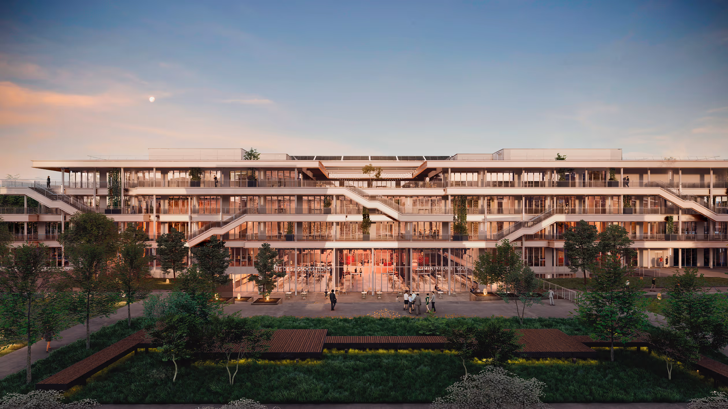 Modern facade of a large multi-storey building with large windows, exterior stairs and greenery, at sunset.