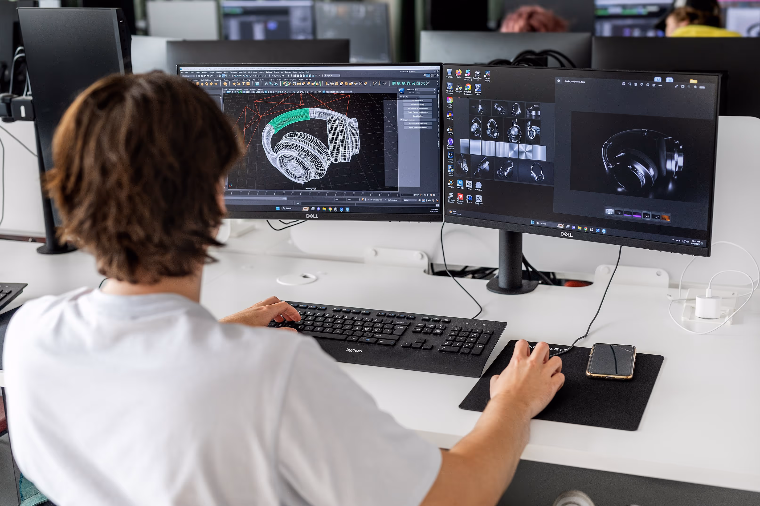 Person working on a 3D headphone model displayed on two computer screens.