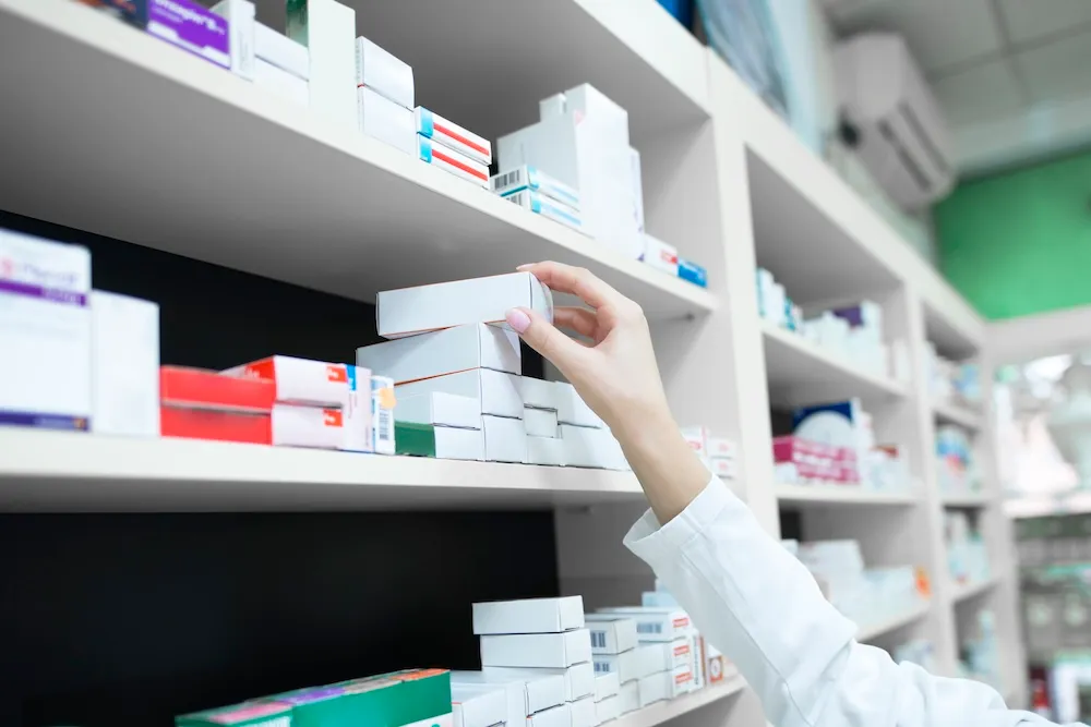 Pharmacist selecting prescription medications from pharmacy shelves in Ontario