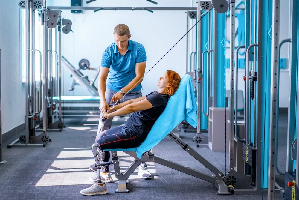 Physiotherapist providing rehabilitation treatment to patient on exercise equipment in Ontario clinic