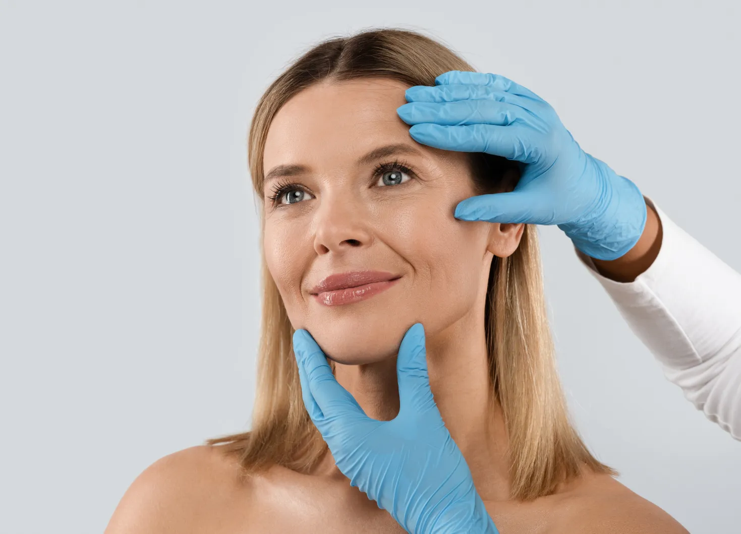 Plastic surgeon assessing a woman's facial features.