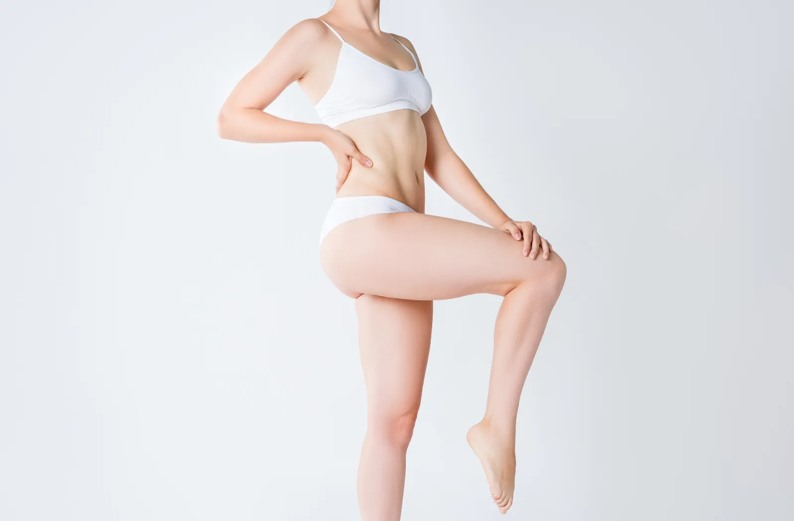 Woman in white lingerie posing to showcase body contour.