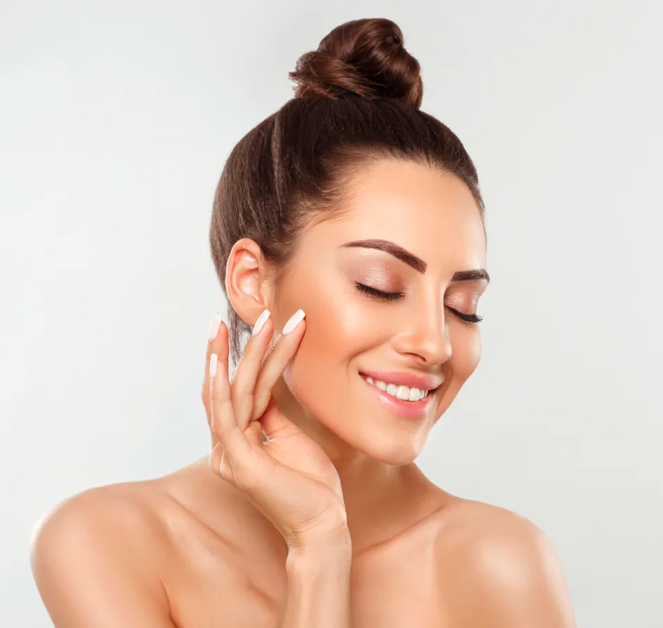Smiling woman touching her face with a glowing complexion.