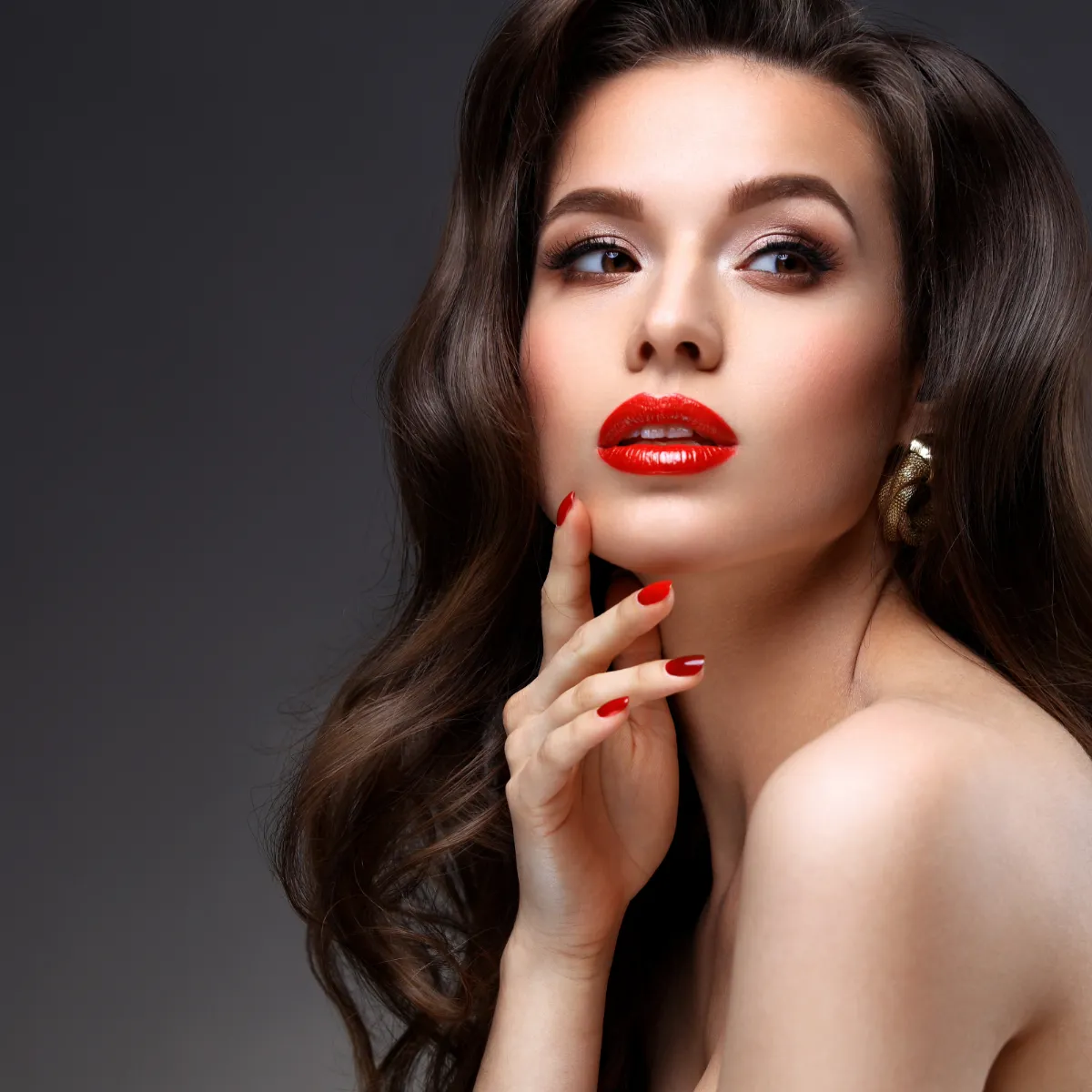 Woman with long brown hair, red lips, and elegant pose.
