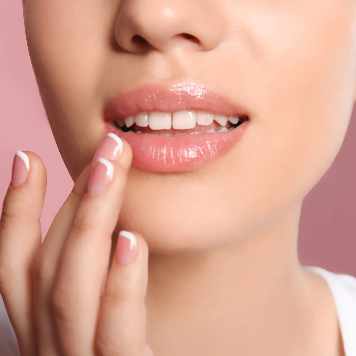 Close-up of a woman's lips and hand, showcasing a glossy lip look.