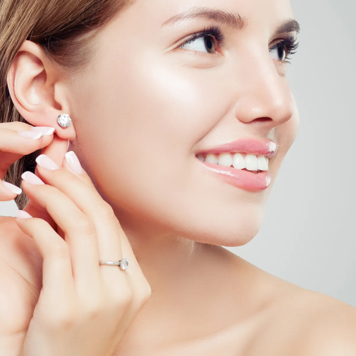 Smiling woman with earrings and a ring.