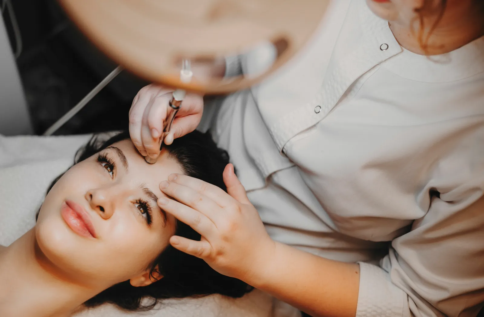 Aesthetician performing a skincare treatment on a woman.
