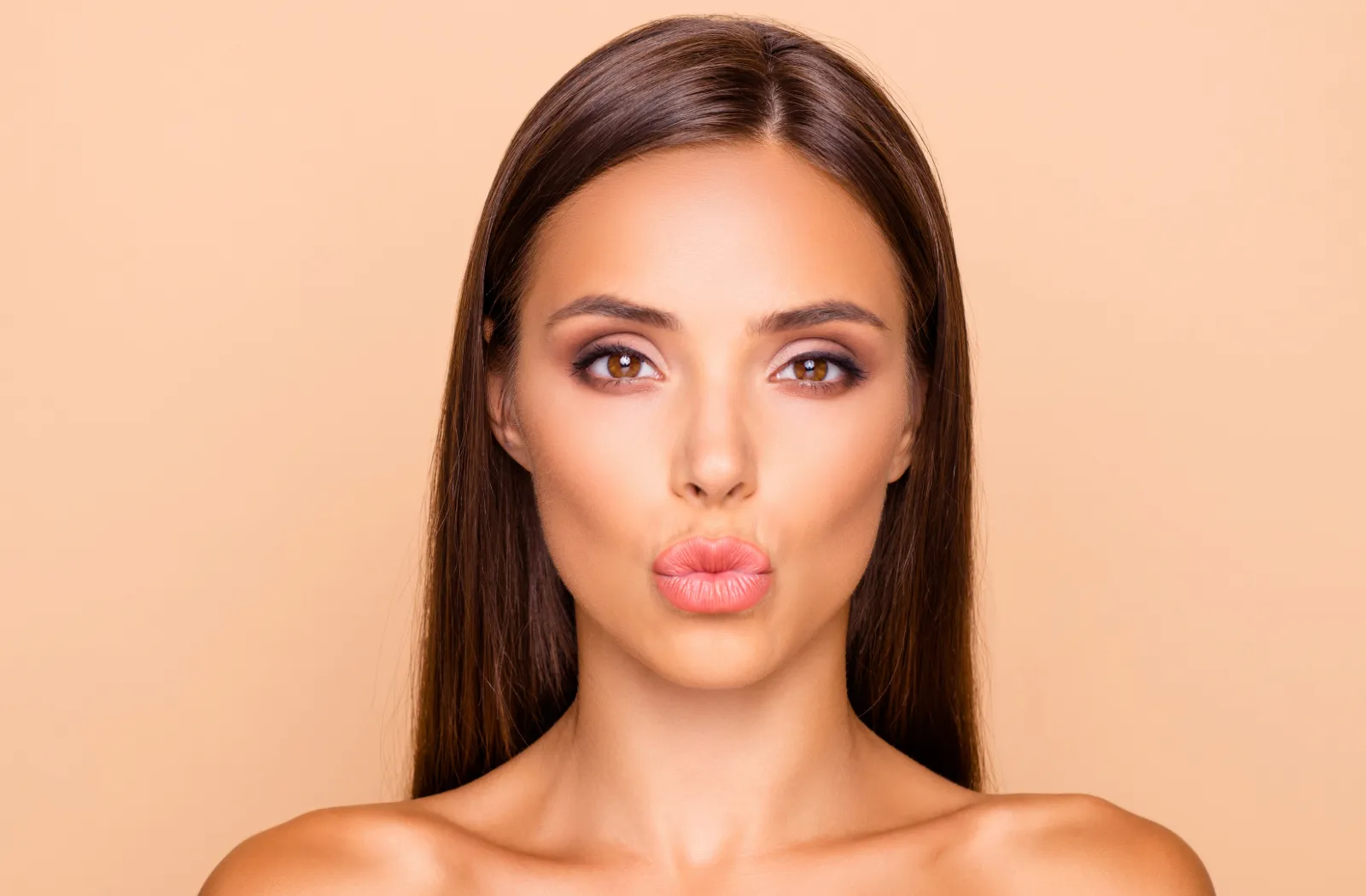 Woman with smooth skin and long hair making a kissing face.