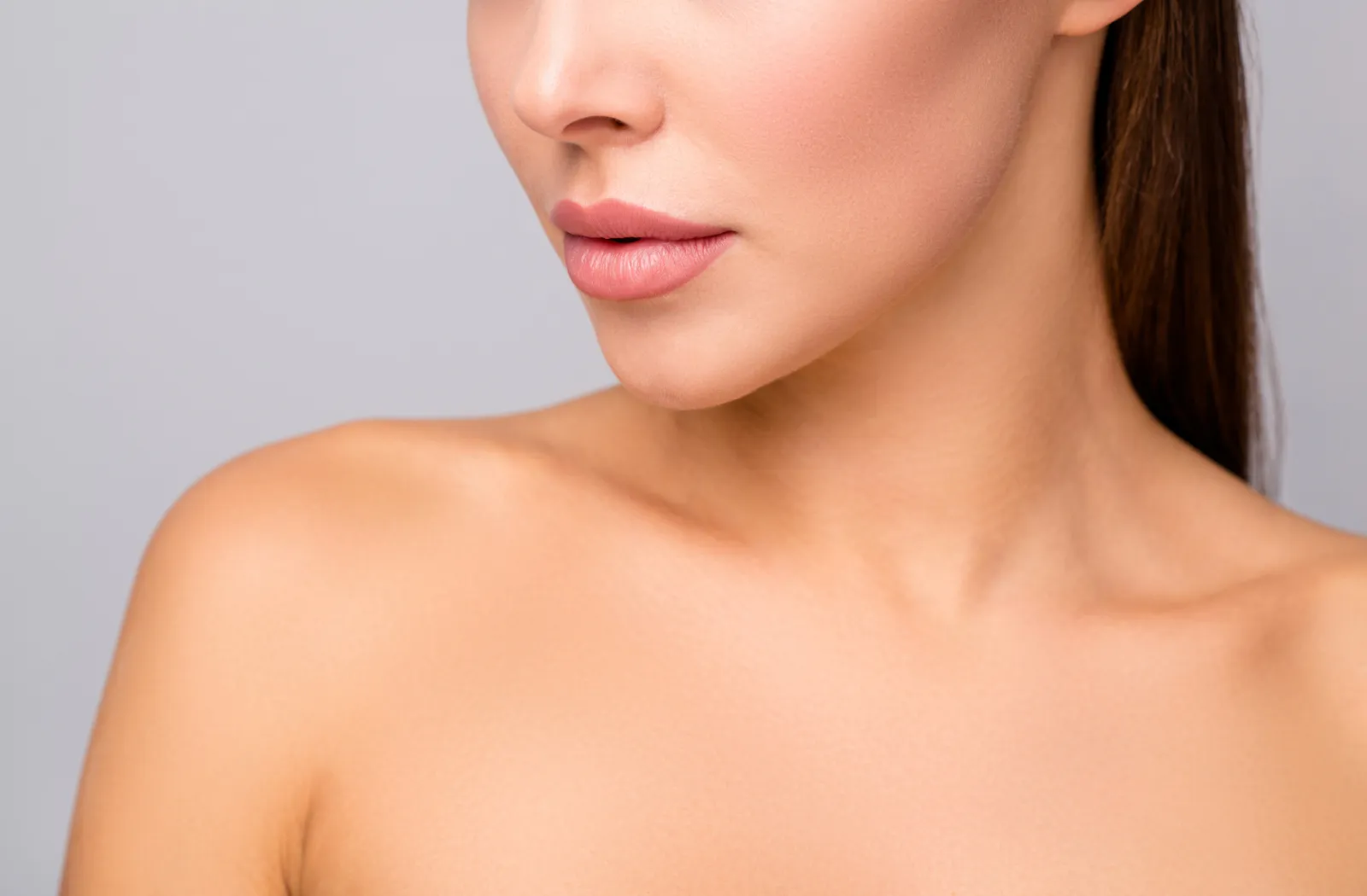 Close-up of a woman's face and shoulder, showcasing smooth skin and natural makeup.